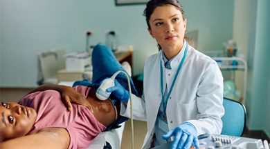 Female doctor examining black woman with sonogram at medical clinic.
