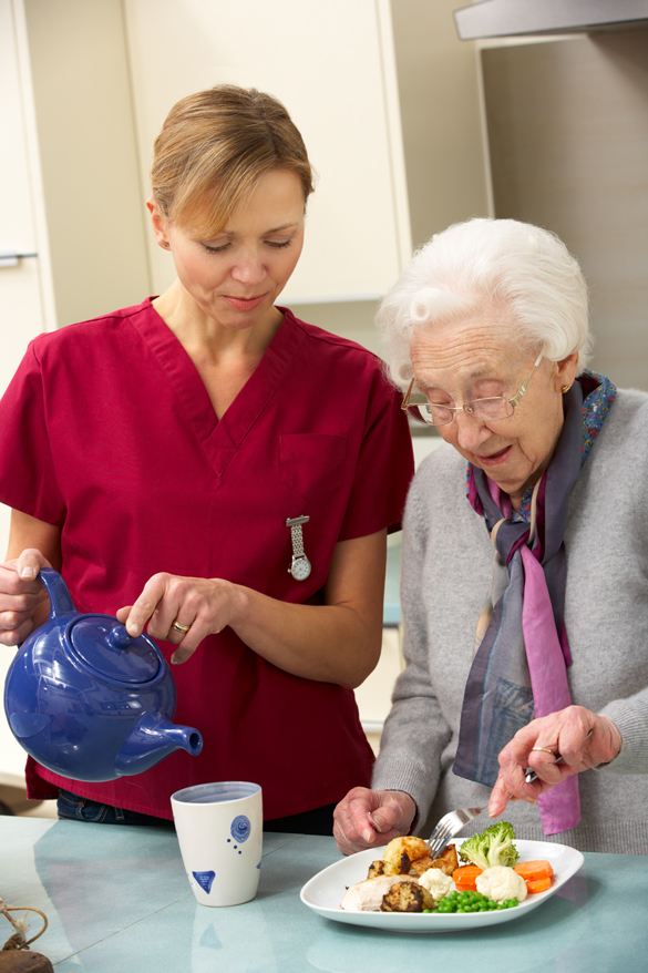 Female OTA assisting an elderly woman with eating food.