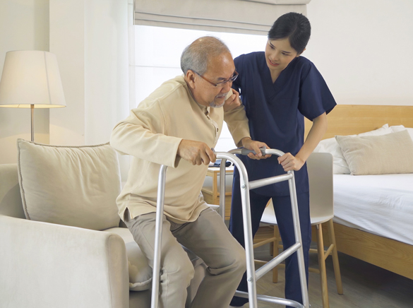 Asian OTA assisting elderly man patient with walker.