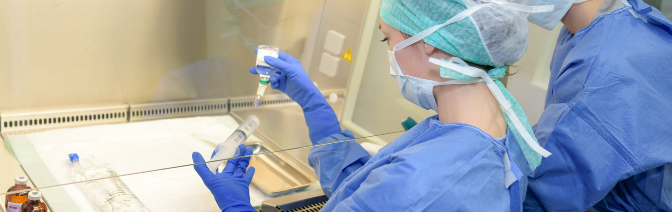 Lab technicians working behind pane of glass.