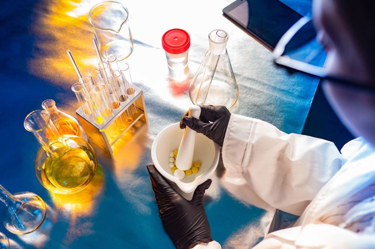 Tablets. Lab technician grinds multi-colored pills. The concept is the preparation of prescription drugs. Creation of individual medicines. The workflow of the medical laboratory