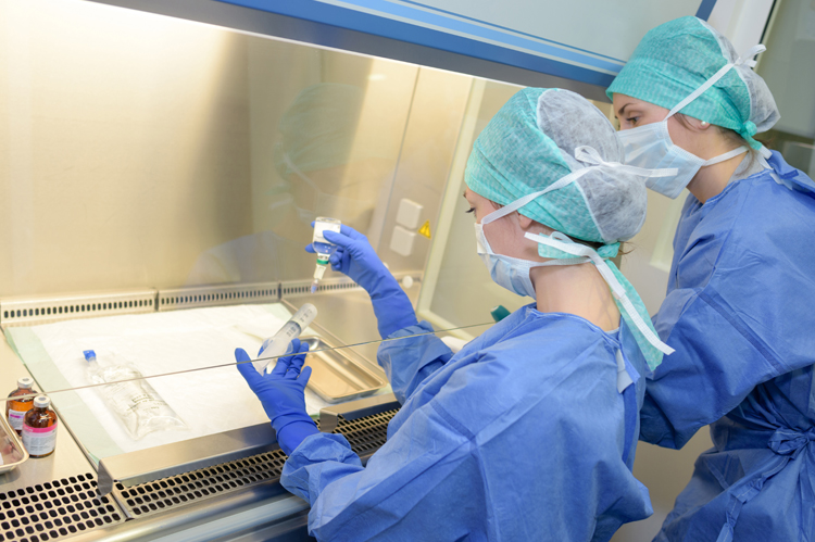 Lab technicians working behind pane of glass.