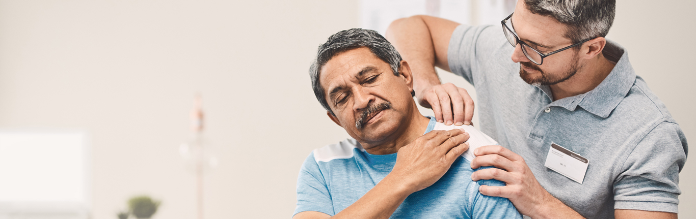 Portrait of physiotherapist doing massage to senior man on massage table.