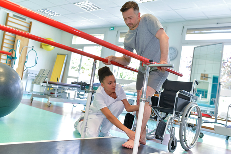 Physical Therapist helping a man walk with guard rails.