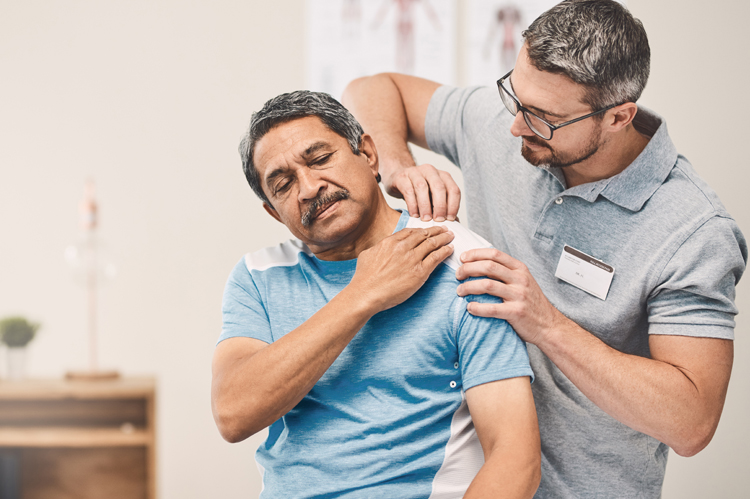 Portrait of physiotherapist doing massage to senior man on massage table.