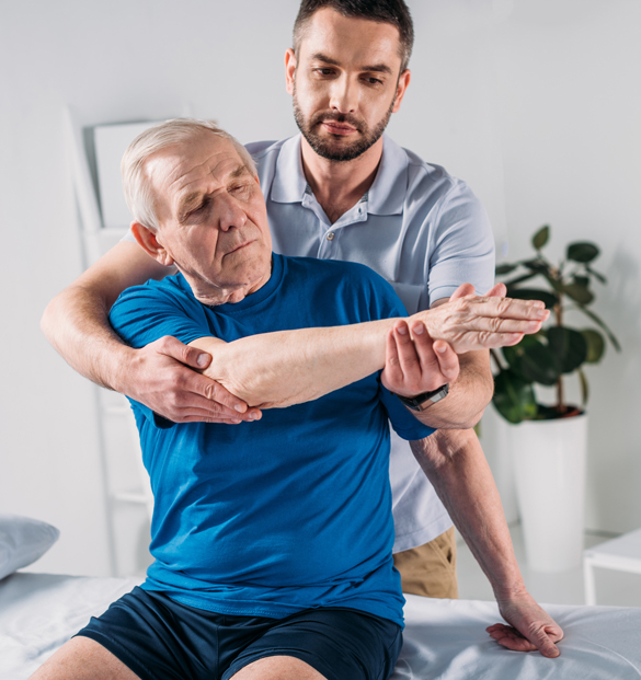 Portrait of physiotherapist doing massage to senior man on massage table.