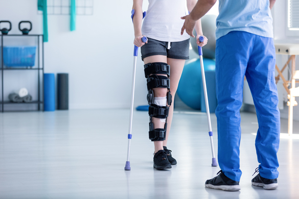 Professional physiotherapist supporting patient with orthopedic problem.
