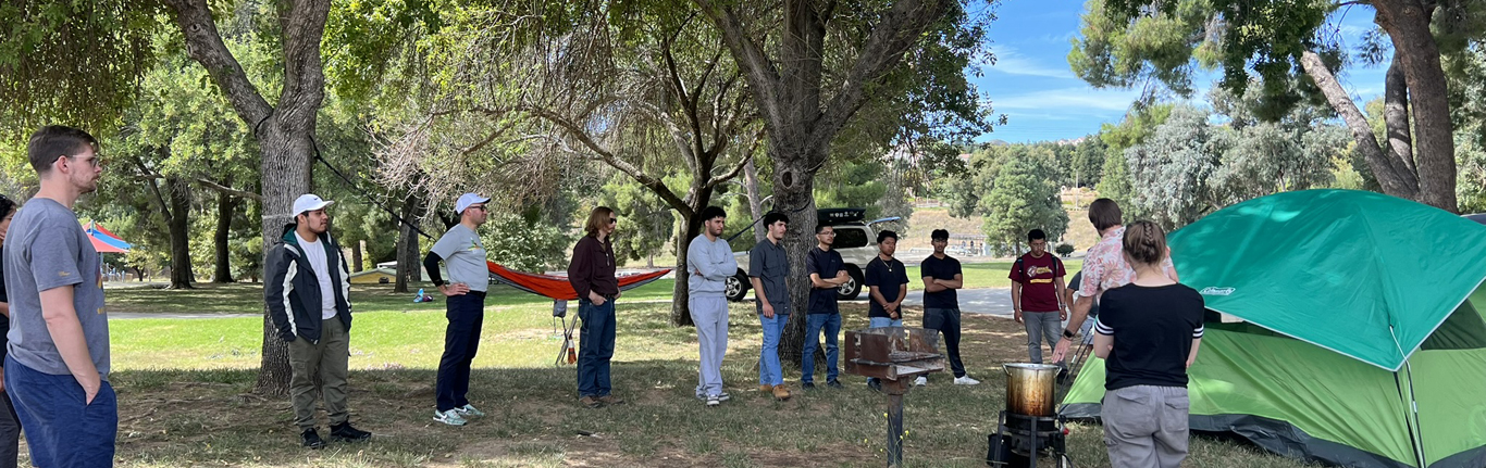 Students standing under trees receiving Recreation Management instruction.