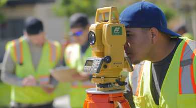 Student surveyor looking through surveying equipment. 
