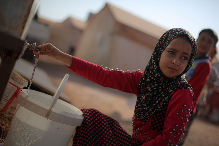 Young girl getting water from a tap.