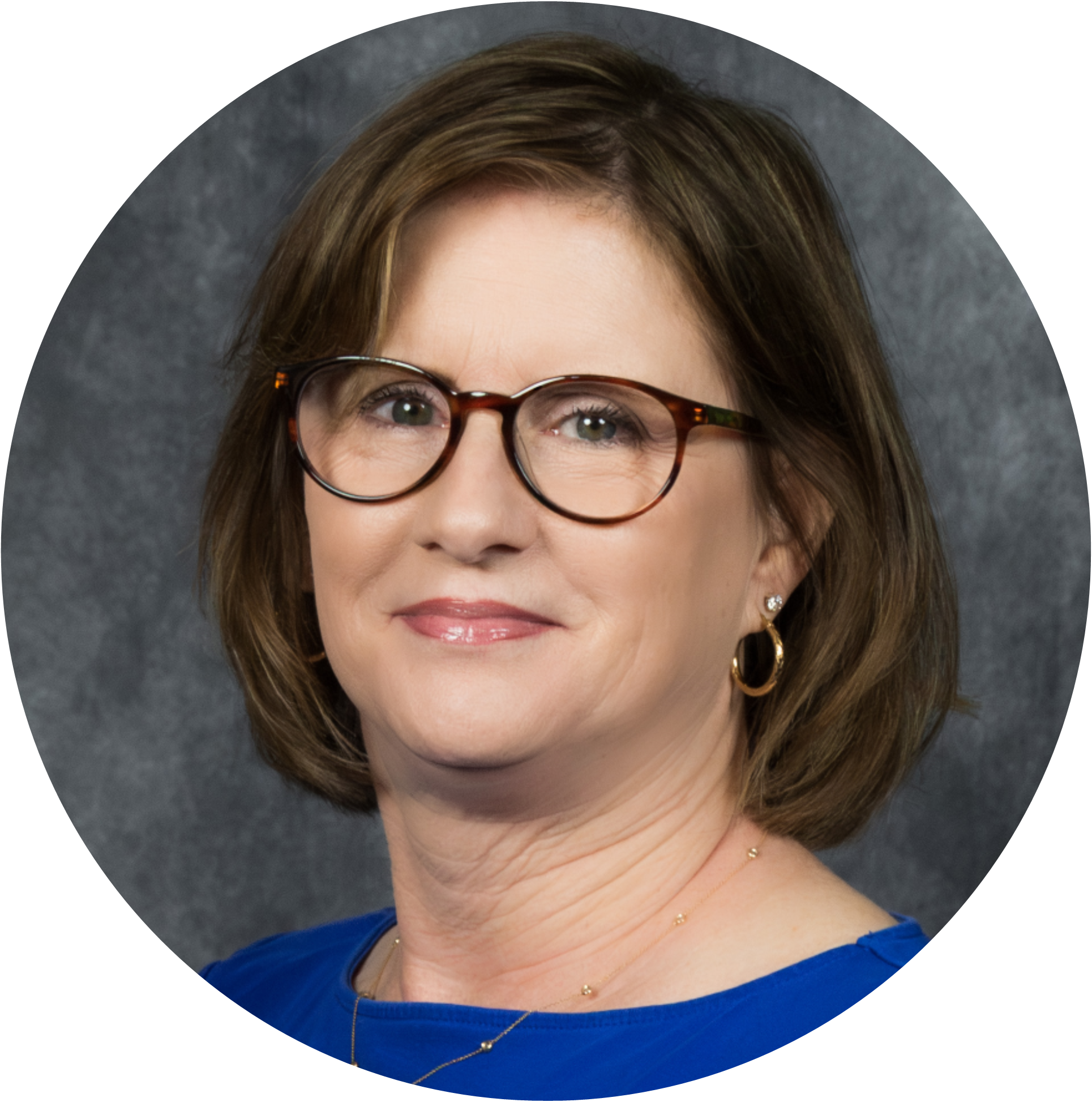 Professional headshot of a woman with glasses and highlighted hair, smiling against a gray backdrop.