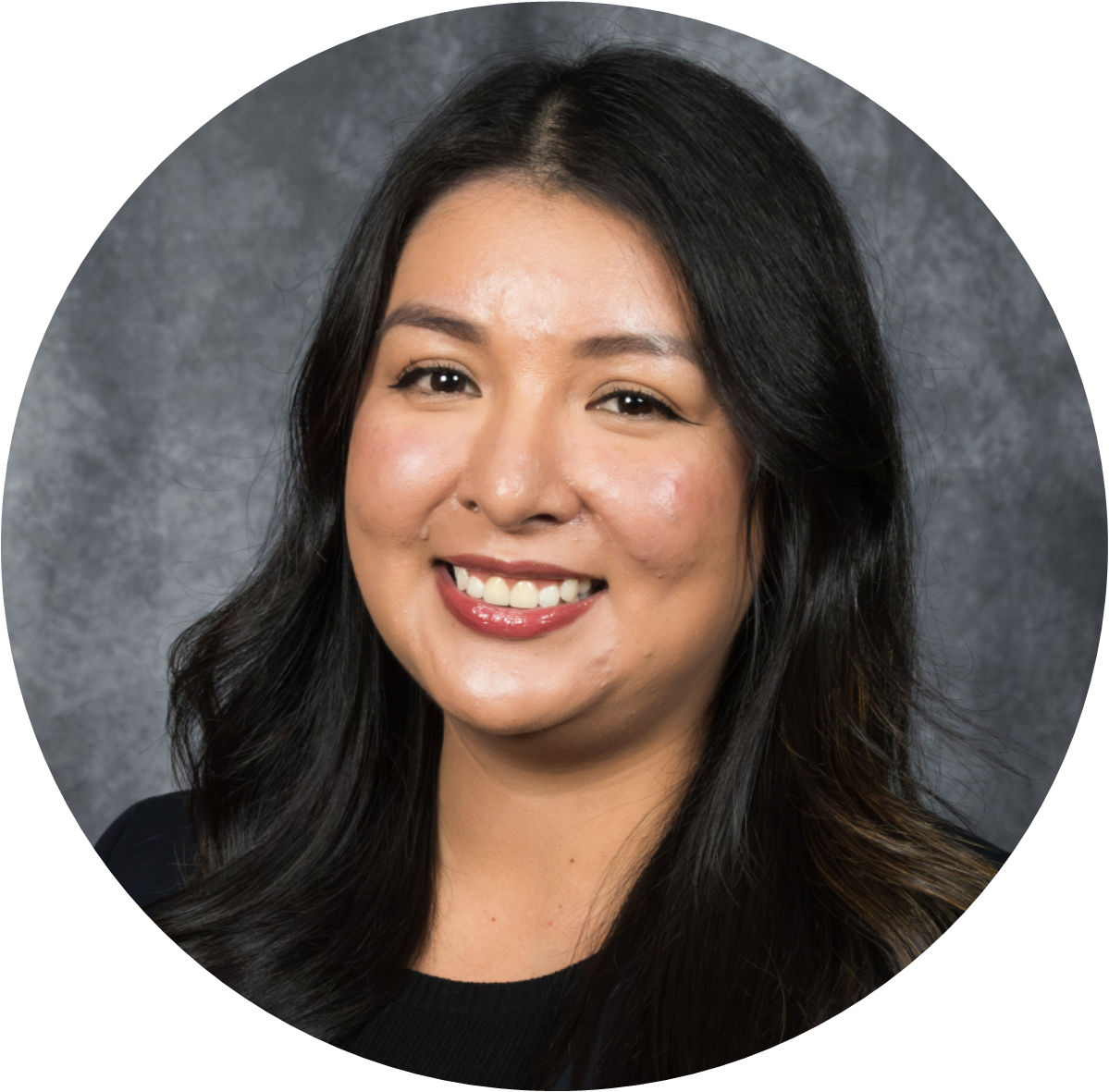 Professional headshot of a smiling woman with long black hair, set against a gray backdrop.