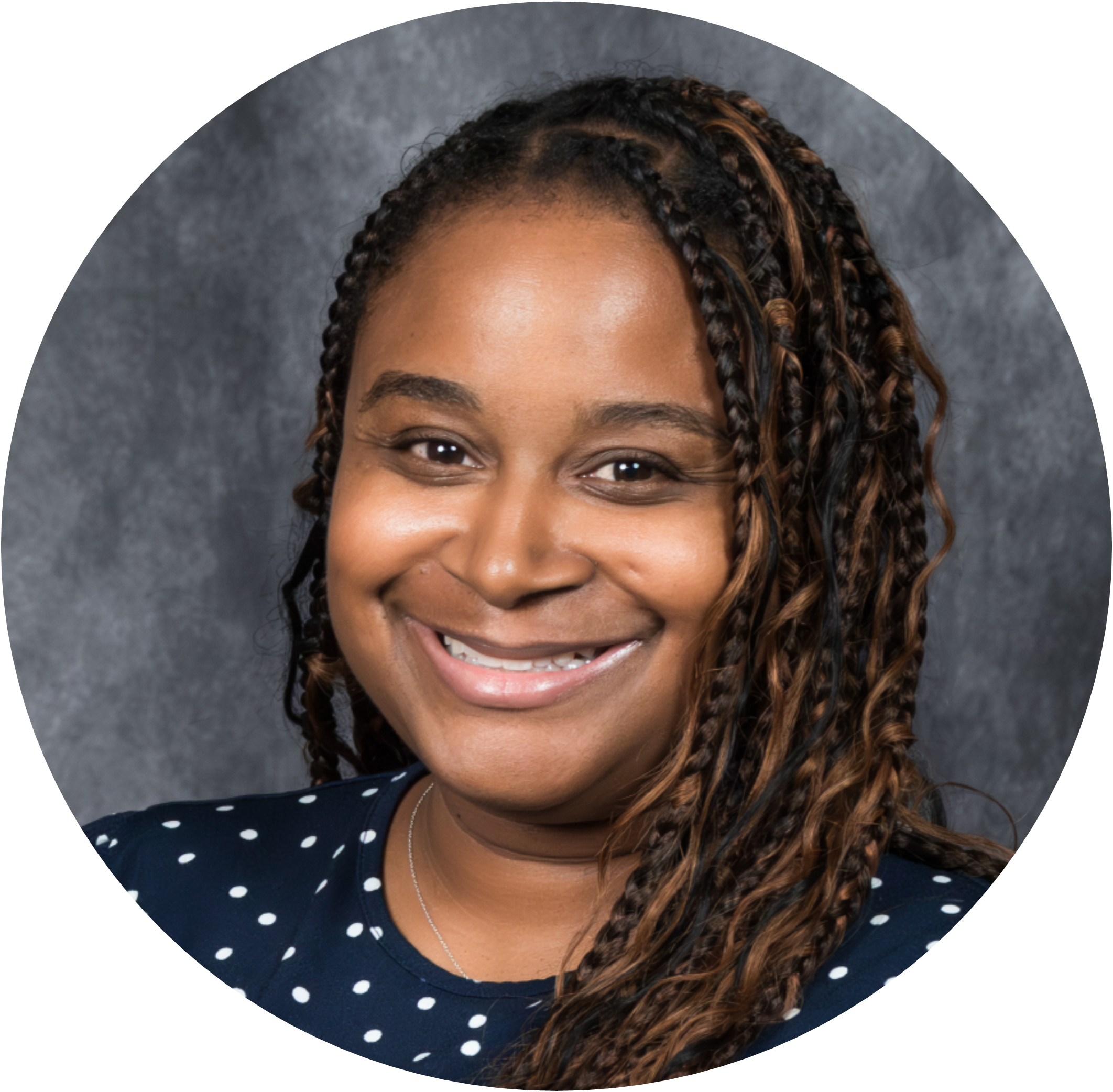 Professional headshot of a smiling woman with braided hair, wearing a polka dot blouse.