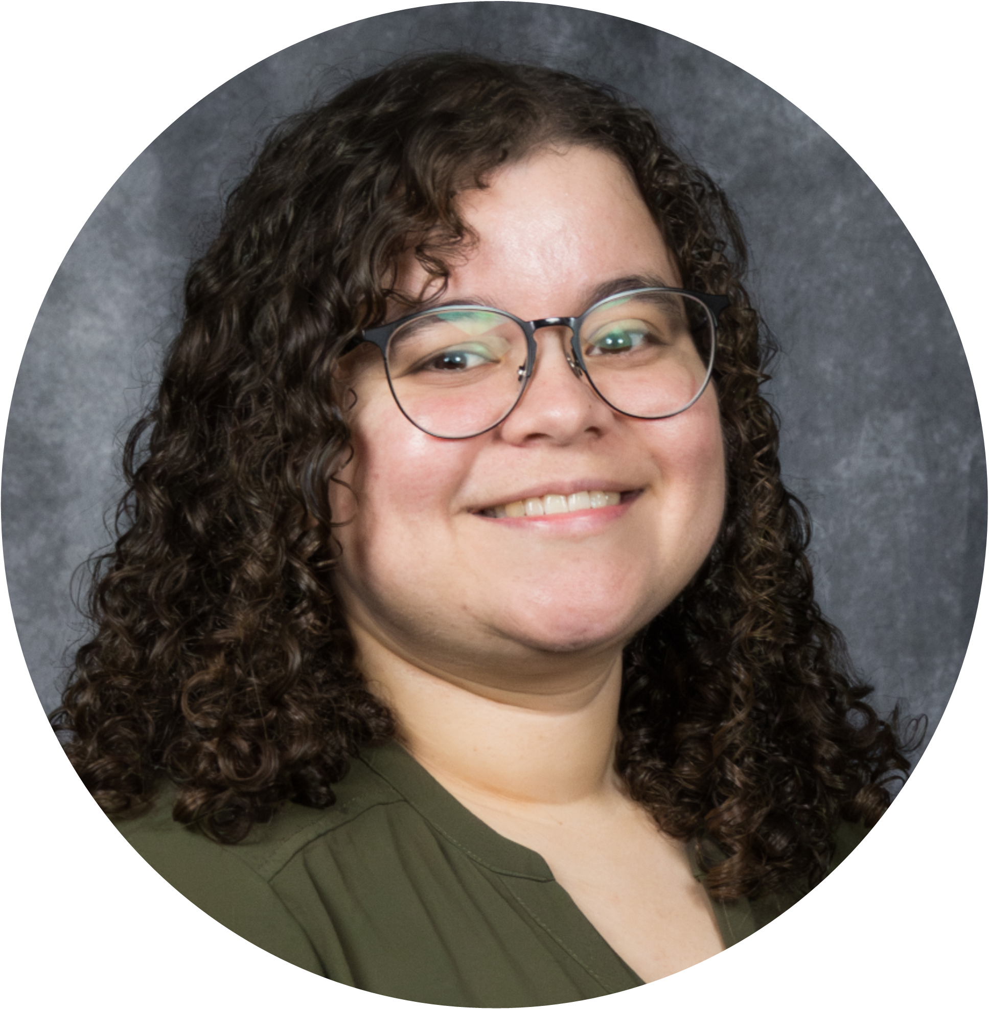 Headshot of a woman with curly hair and glasses, smiling against a gray background.