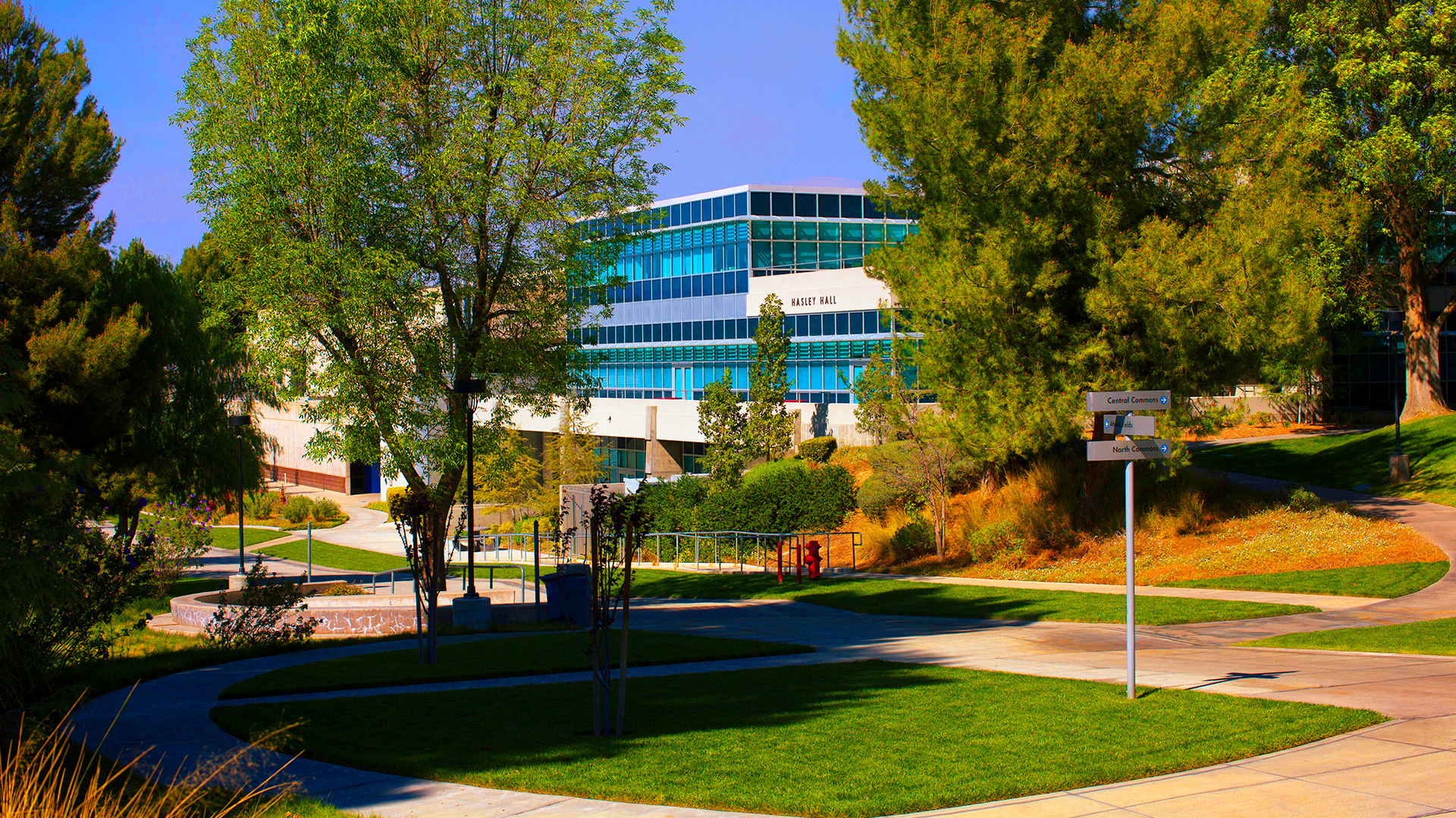Modern architectural exterior of a university center during sunset, showcasing large windows and contemporary design.