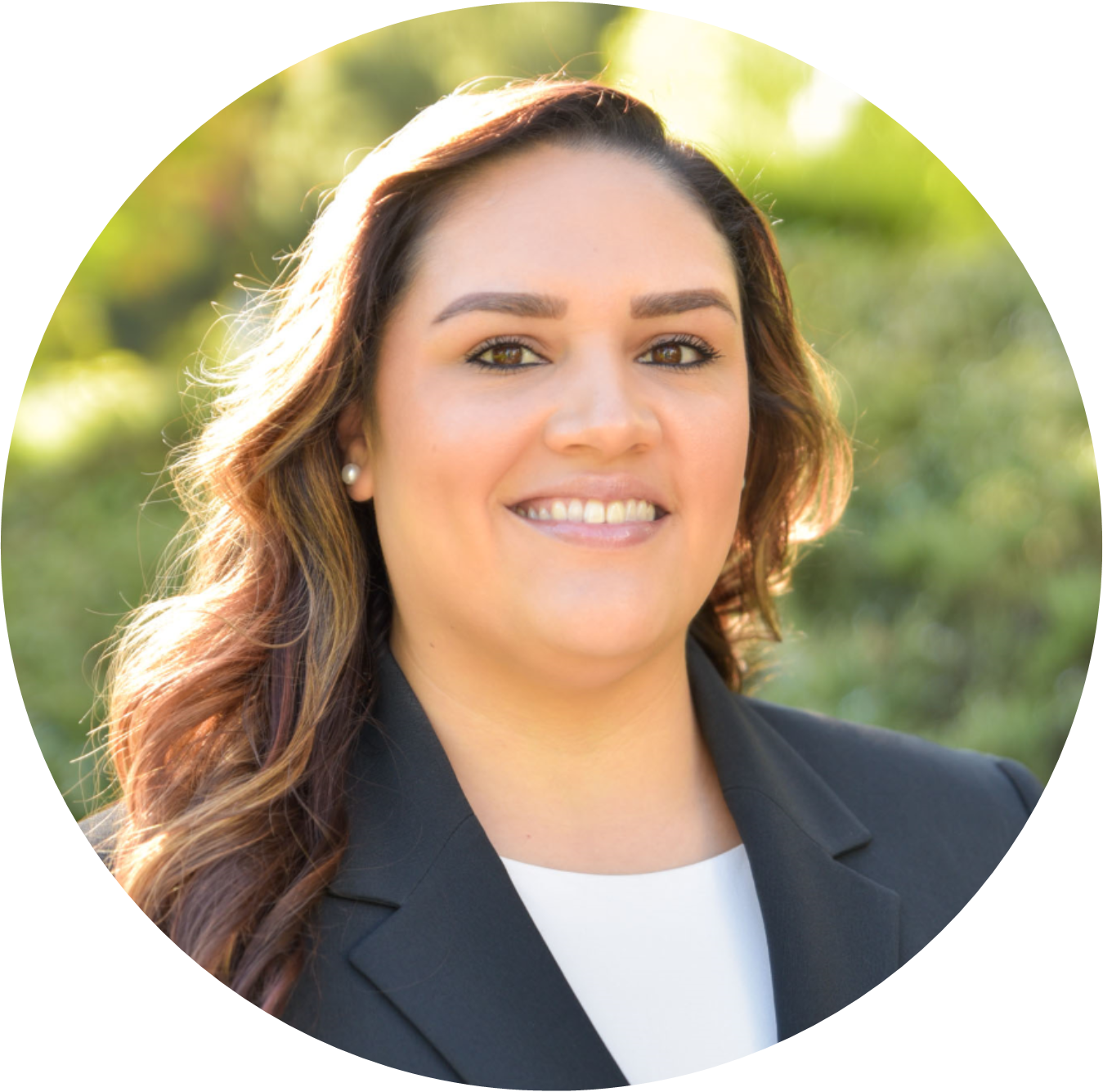 Professional headshot of a smiling woman in a blazer, with a blurred green background.