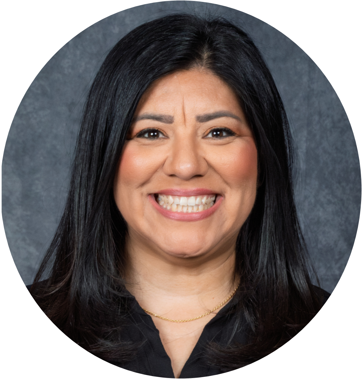 Portrait of a woman with long black hair smiling warmly against a textured gray background.