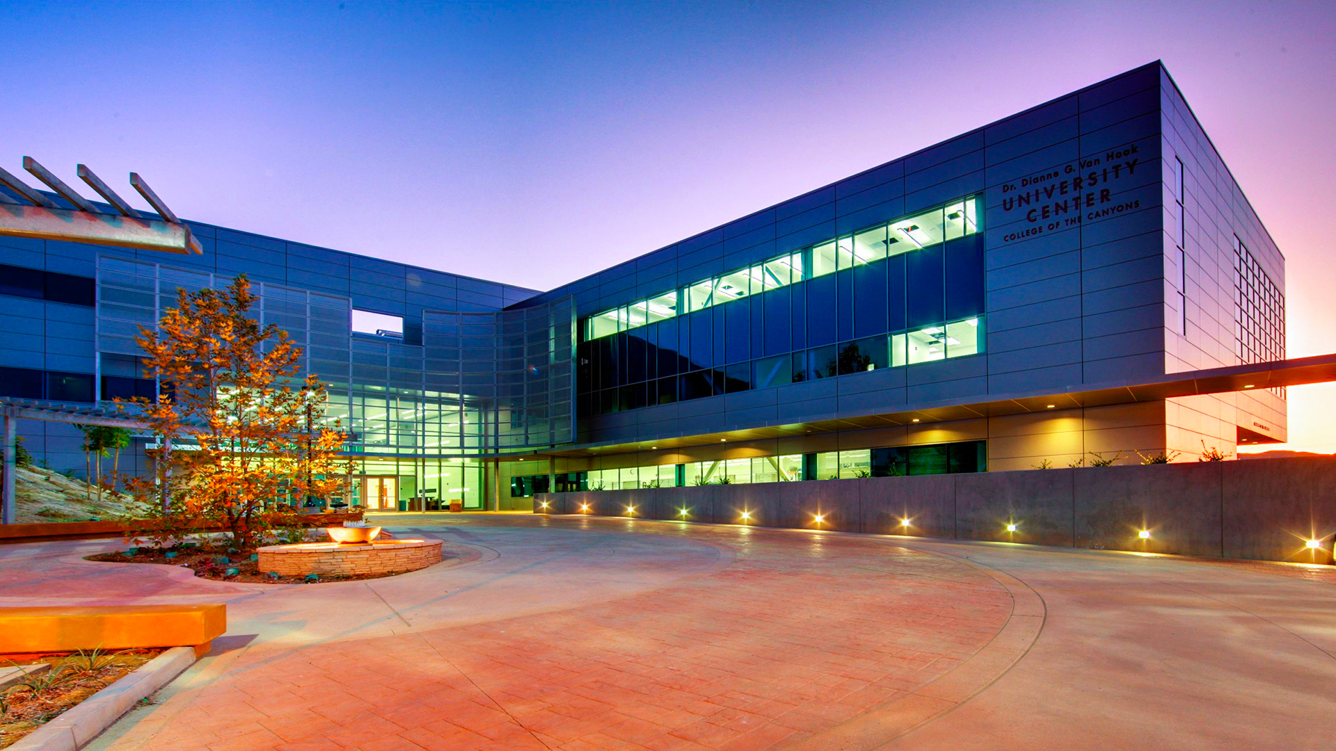 Modern architectural exterior of a university center during sunset, showcasing large windows and contemporary design.