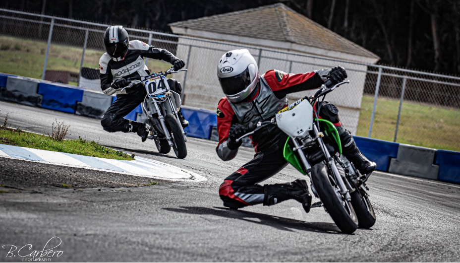 Image of Peter on a mini motorcycle racing around a track with another motorcycle rider right behind him.
