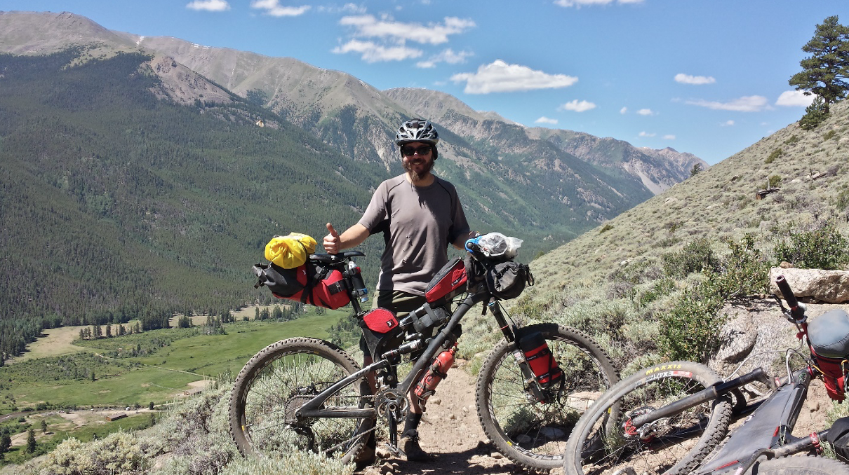 Mountain bike rider standing on a mountain trail holding his mountain bike.