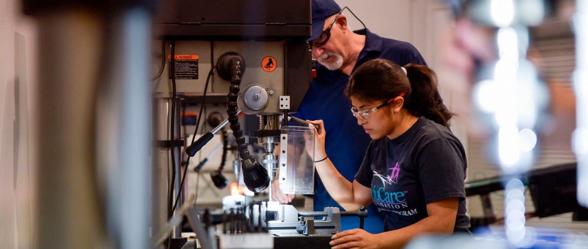 A female student operates equipment under the watchful eye of a faculty member at the Interim Advanced Technology Center.