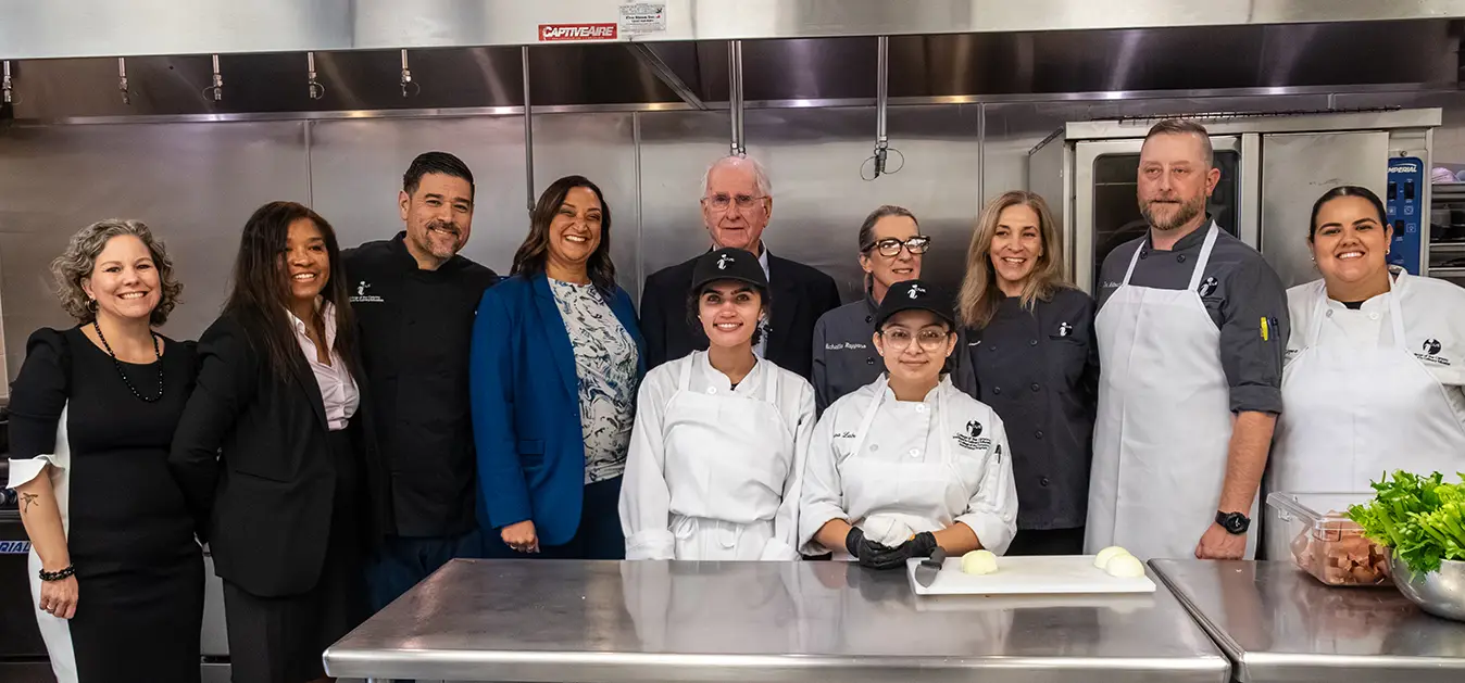 Gary Cusumano (center, rear) poses for a group shot in a teaching kitchen.