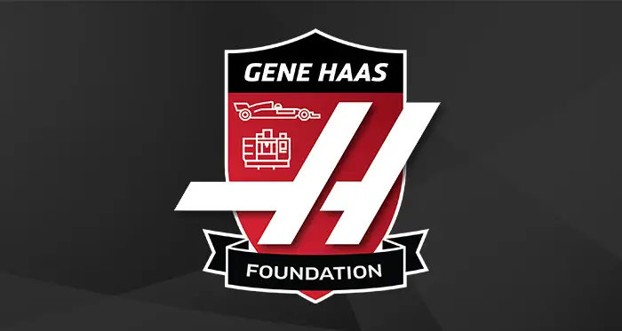Gene Haas Foundation logo in a red-and-black shield with stylized “GH” initials, plus small icons of a race car and an engine.