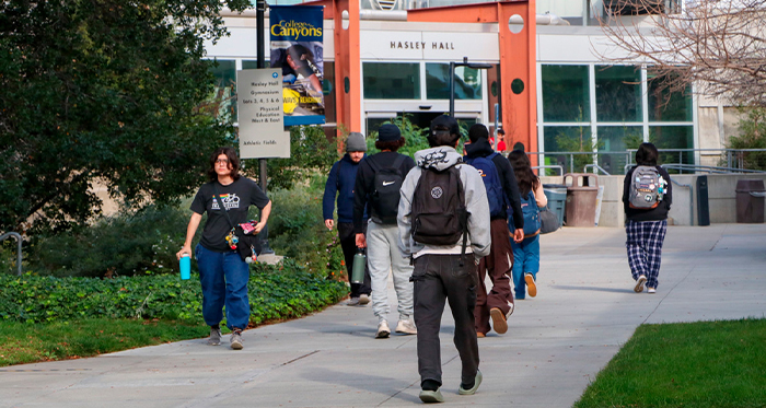 Students walking on a campus pathway toward Hasley Hall.