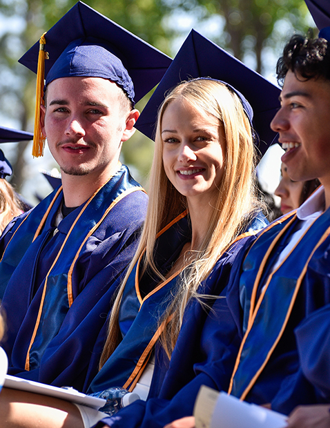 Male and female graduates smile during commencement.