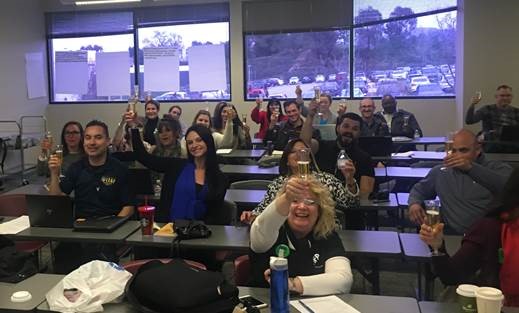 a group of committee members from IE quantity squared raising glasses of sparkling cider and smiling toward the camera for a toast