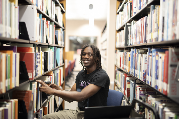 Student, both a student and employee, working in library.