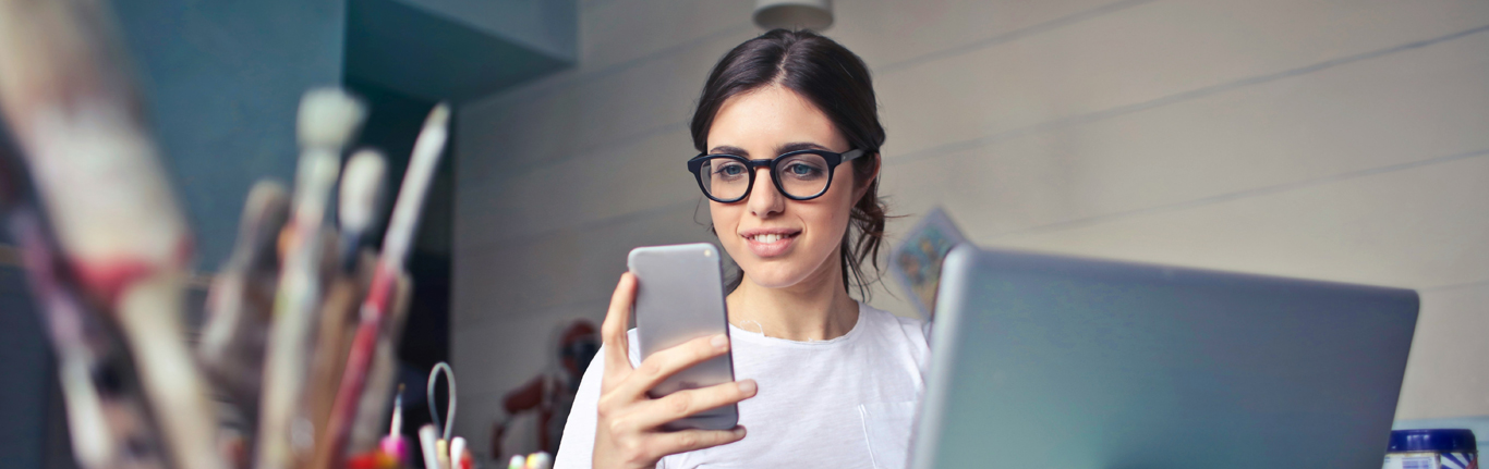 Student on mobile device, at computer. 