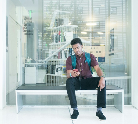 College student sitting on bench looking at iPhone.