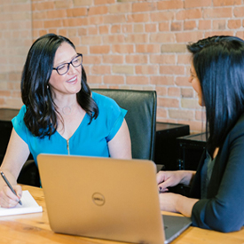 Employer talking with student at a laptop.