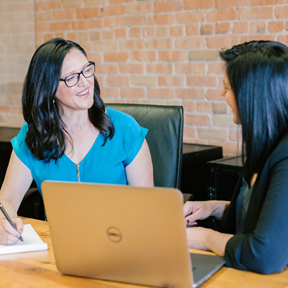 Employer talking with student at a laptop.