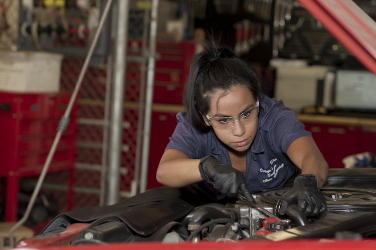 Automotive student working under the hood of a car.