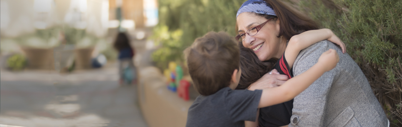 Children hugging their teacher at Early Childhood Education.