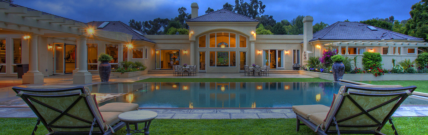 Sprawling mansion at night with pool.