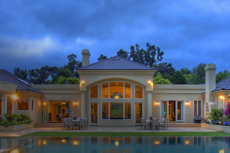 Sprawling mansion at night with pool.