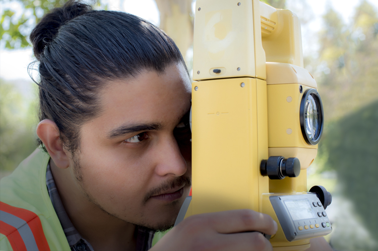 Surveyor looking through surveying equipment.