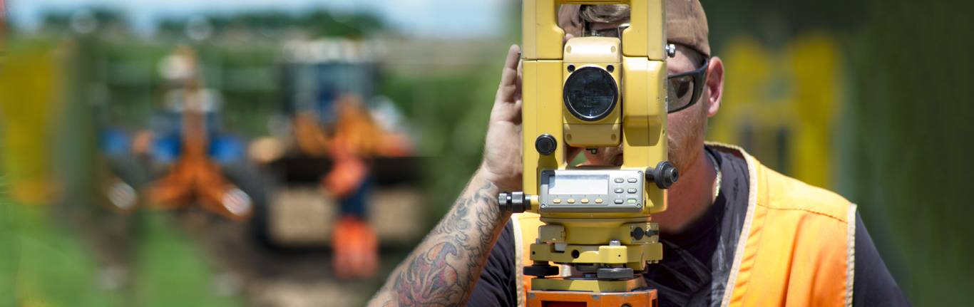 Surveyor looking through surveying equipment.